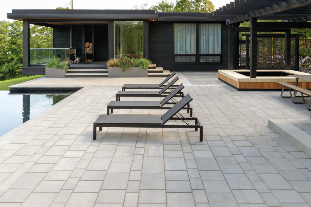 Immagine di un patio o portico minimalista dietro casa con lastre di cemento e una pergola