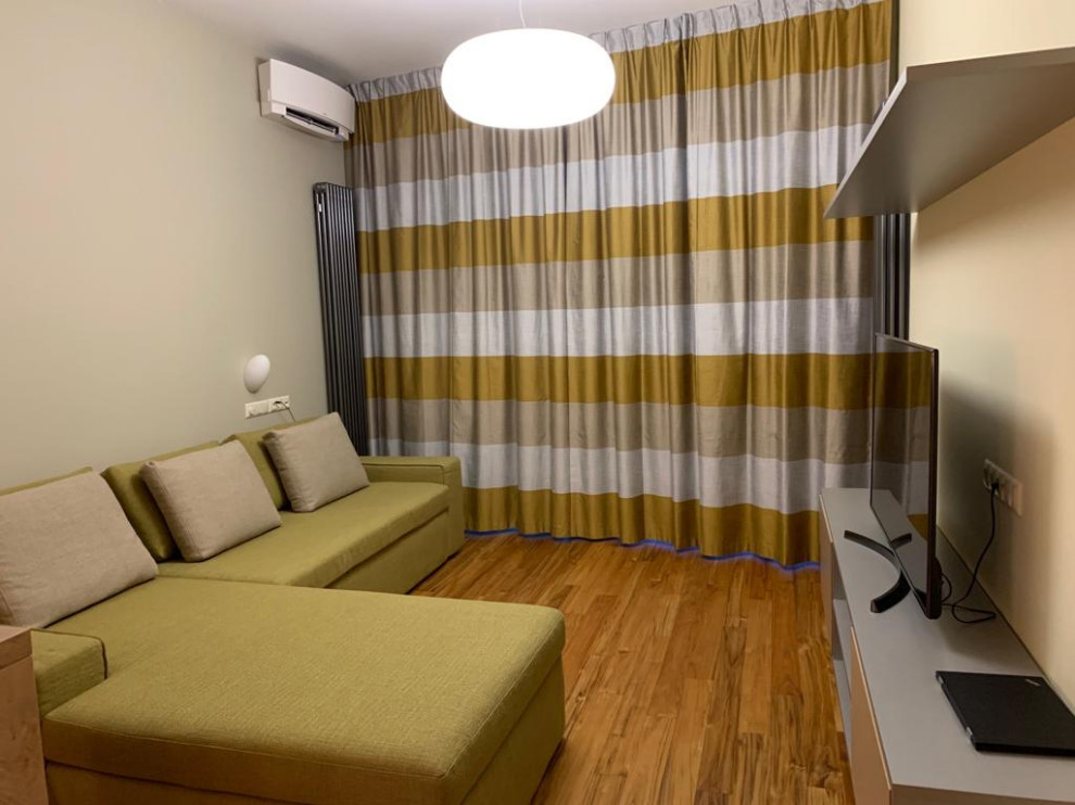 Modern inredning av ett mellanstort allrum med öppen planlösning, med ett finrum, beige väggar, mellanmörkt trägolv, en fristående TV och beiget golv