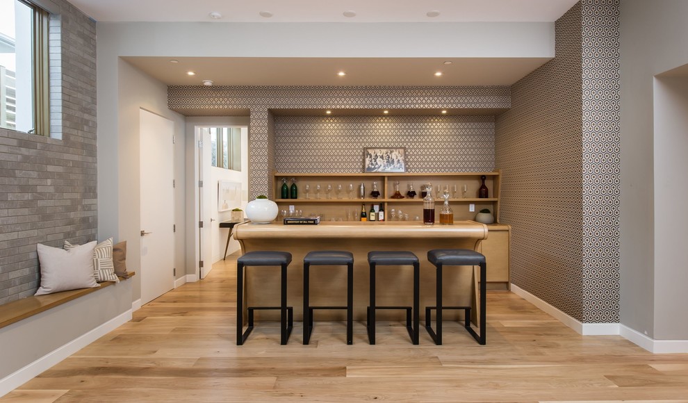 This is an example of a large midcentury galley seated home bar in Los Angeles with an undermount sink, medium wood cabinets, wood benchtops, multi-coloured splashback and medium hardwood floors.