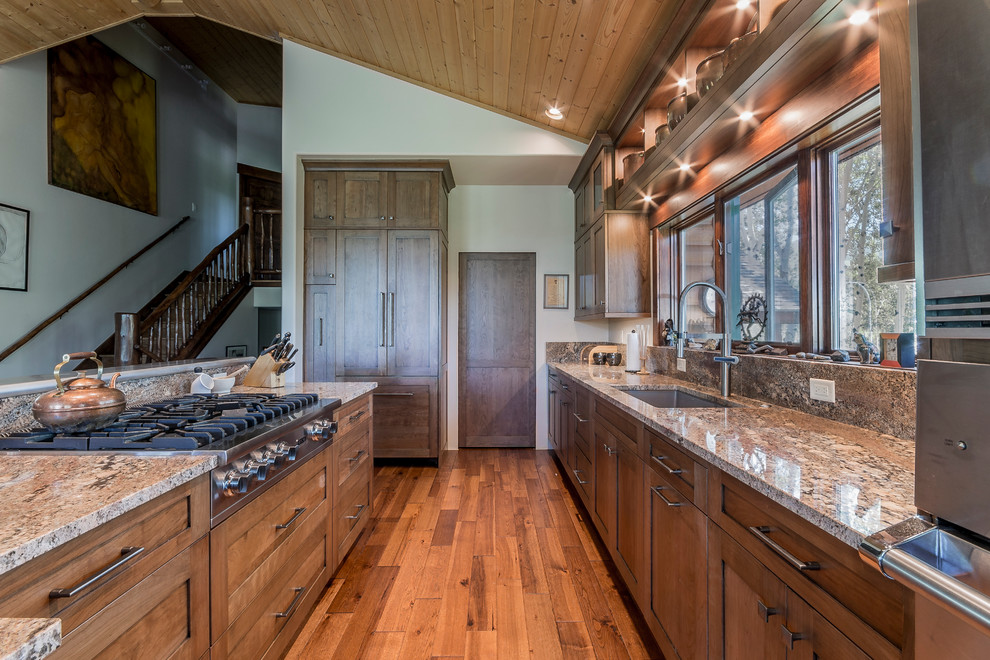Photo of an expansive transitional l-shaped open plan kitchen in Denver with shaker cabinets, orange cabinets, granite benchtops, stainless steel appliances and medium hardwood floors.