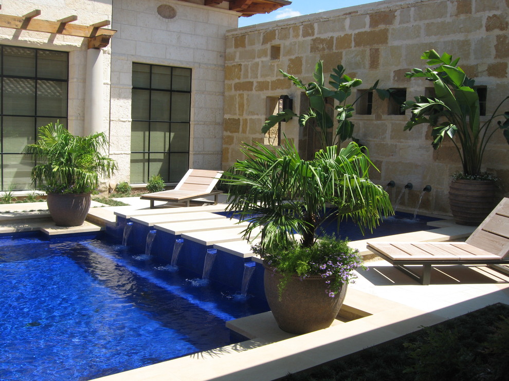 Tropical custom-shaped pool in Dallas with a water feature.