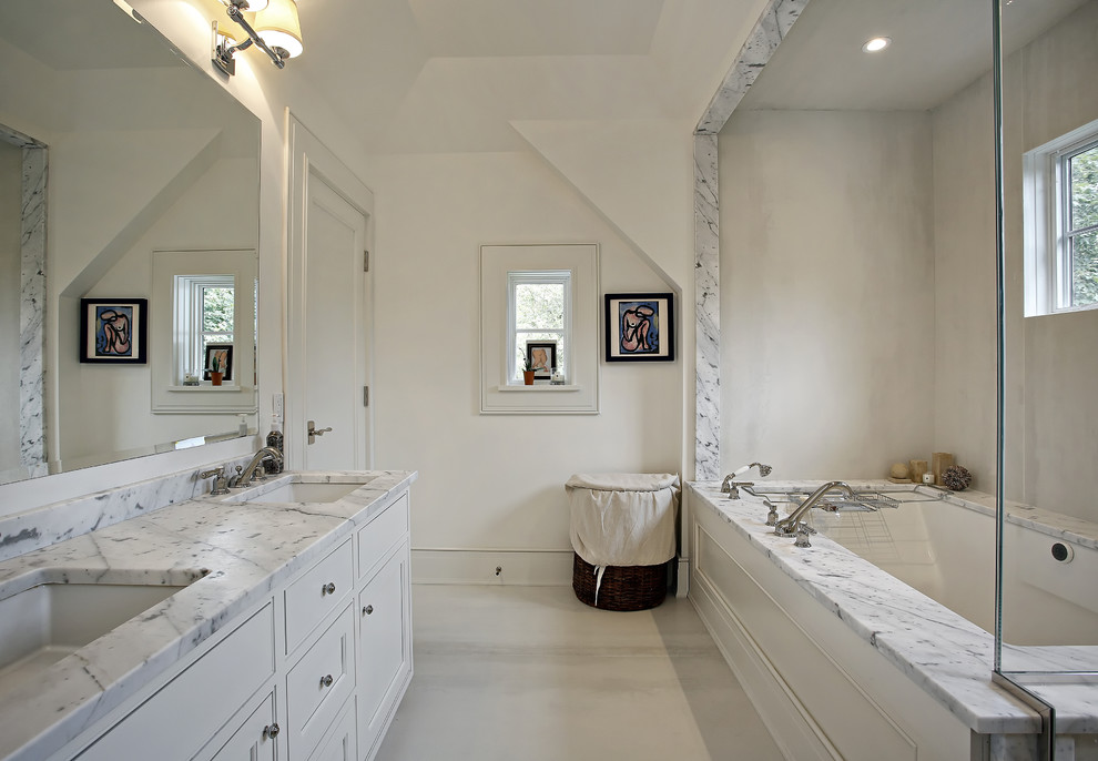 This is an example of a traditional bathroom in New York with an undermount sink, raised-panel cabinets, white cabinets and an undermount tub.