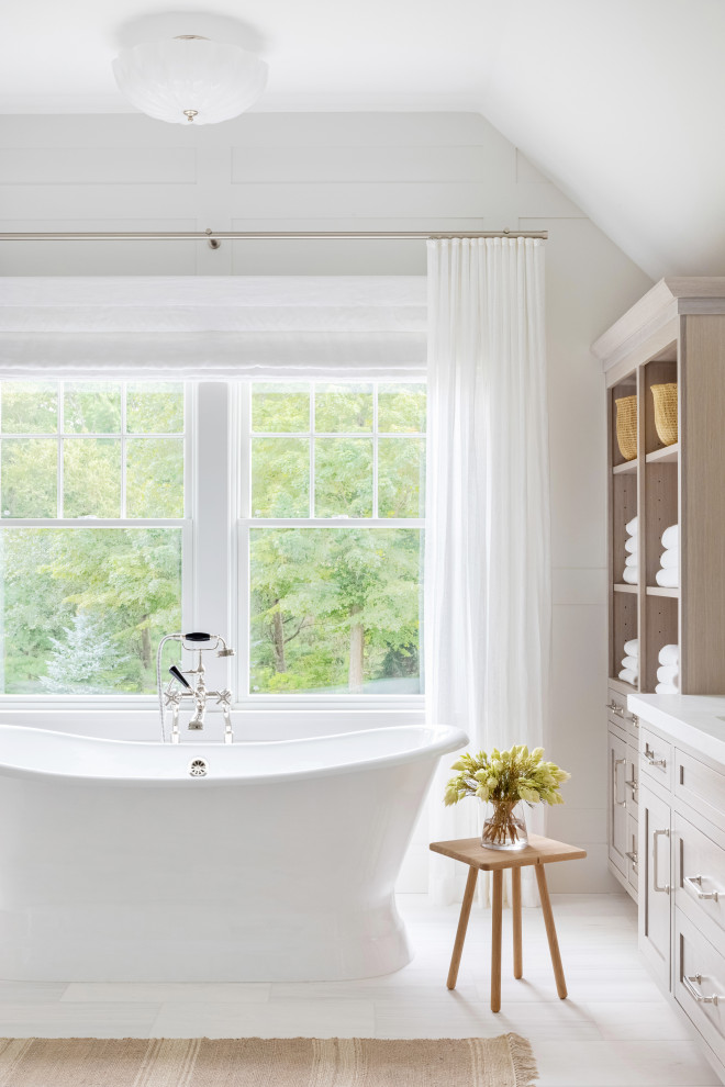Expansive traditional master bathroom in New York with recessed-panel cabinets, light wood cabinets, a claw-foot tub, an alcove shower, a one-piece toilet, white tile, white walls, an integrated sink, marble benchtops, white floor, a hinged shower door and white benchtops.