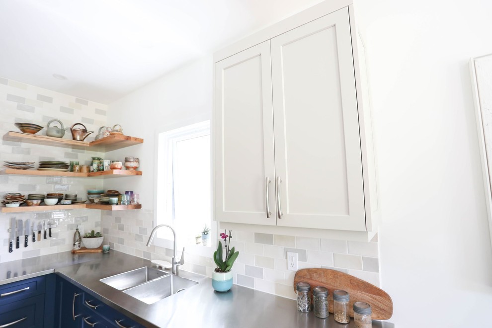 Mid-sized transitional l-shaped light wood floor and beige floor open concept kitchen photo with an integrated sink, shaker cabinets, blue cabinets, stainless steel countertops, ceramic backsplash, stainless steel appliances, an island and gray countertops