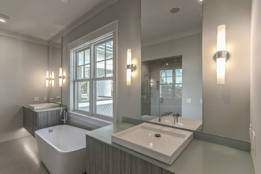This is an example of a large contemporary master bathroom in Charleston with flat-panel cabinets, grey cabinets, gray tile, porcelain tile, engineered quartz benchtops, a freestanding tub, an alcove shower, grey walls, porcelain floors, a vessel sink, grey floor and a hinged shower door.