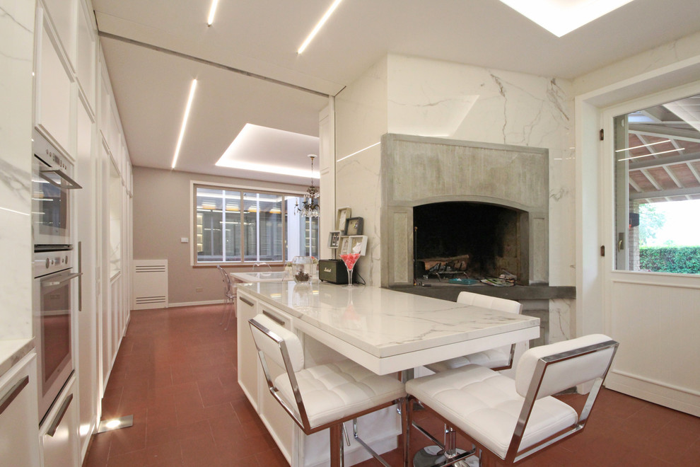 Photo of an expansive traditional eat-in kitchen in Milan with recessed-panel cabinets, marble benchtops, white appliances, ceramic floors, with island, red floor and white benchtop.
