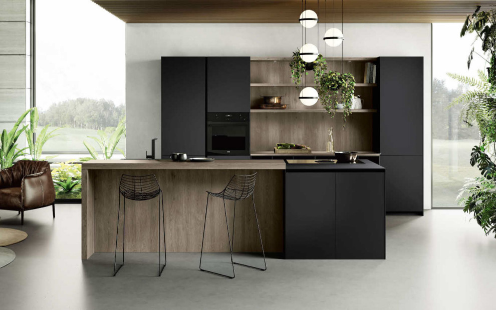 Design ideas for a mid-sized modern galley open plan kitchen in Orange County with a single-bowl sink, flat-panel cabinets, black cabinets, quartz benchtops, black appliances, concrete floors, with island and black benchtop.