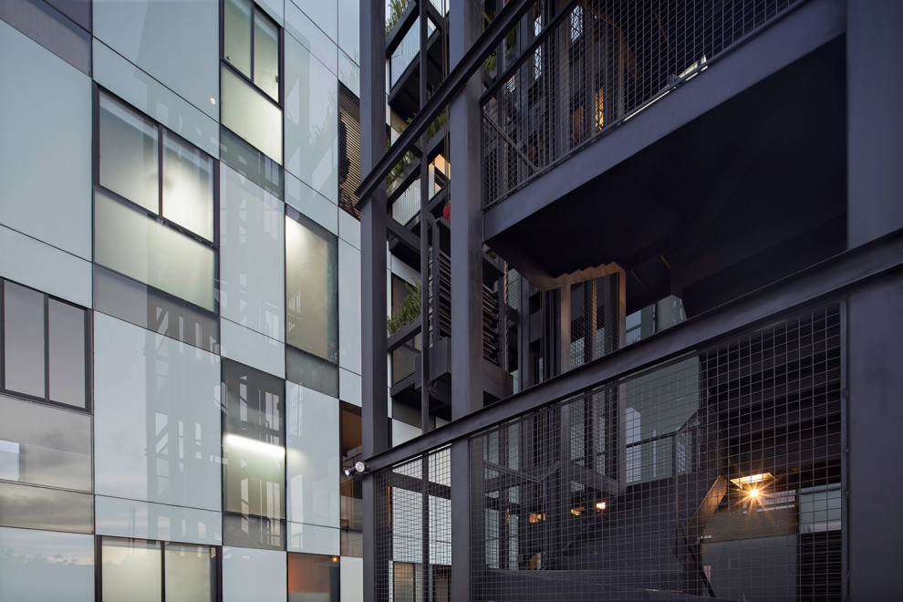 Foto della facciata di un appartamento grande nero moderno a piani sfalsati con rivestimento in vetro, tetto piano, copertura in metallo o lamiera, tetto nero, pannelli e listelle di legno e scale