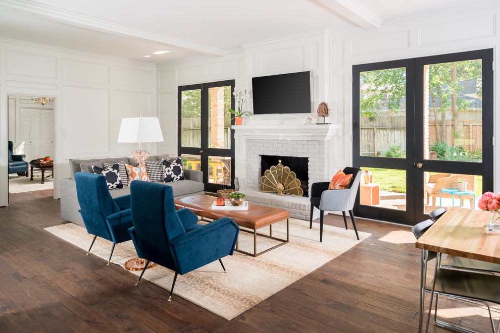 Inspiration for a transitional family room in Houston with white walls, dark hardwood floors, a standard fireplace, a brick fireplace surround, a wall-mounted tv and brown floor.