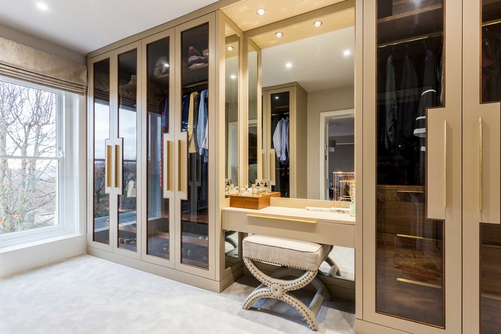 Mid-sized modern gender-neutral dressing room in Other with glass-front cabinets, carpet and beige floor.