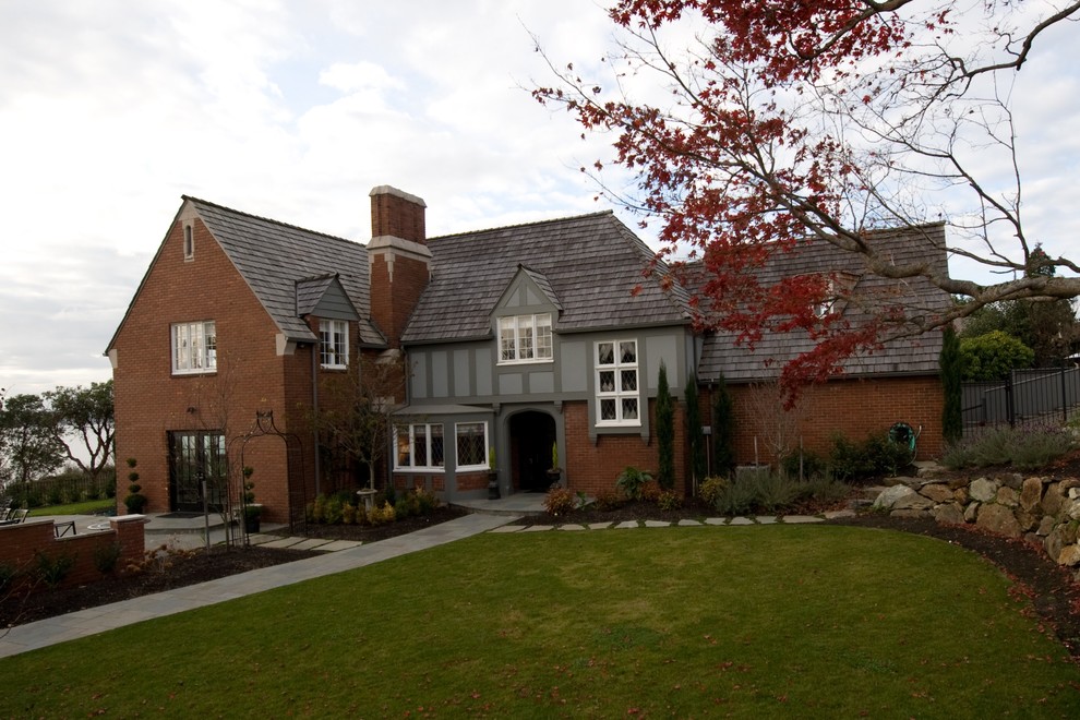 This is an example of a large traditional two-storey brick red exterior in Seattle with a gambrel roof.