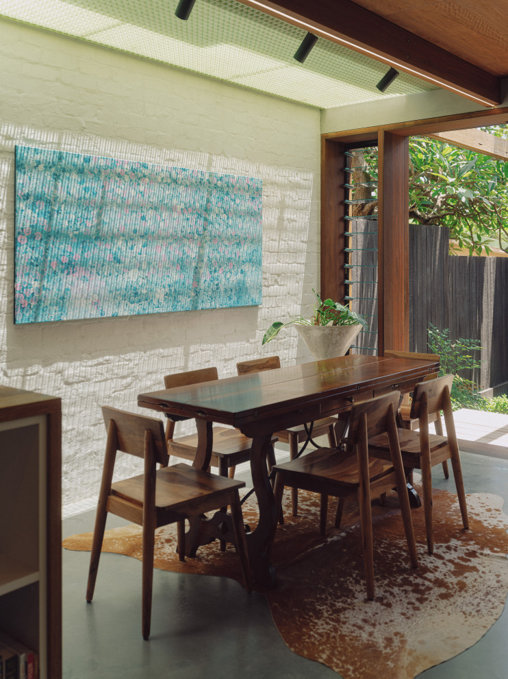 Photo of an asian dining room in Sydney with white walls, concrete floors, grey floor, wood and brick walls.