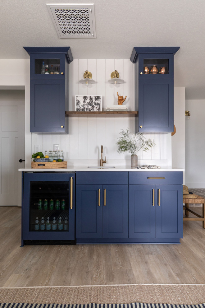 Design ideas for a small nautical single-wall wet bar in San Diego with a submerged sink, shaker cabinets, blue cabinets, engineered stone countertops, white splashback, wood splashback, vinyl flooring, beige floors and white worktops.