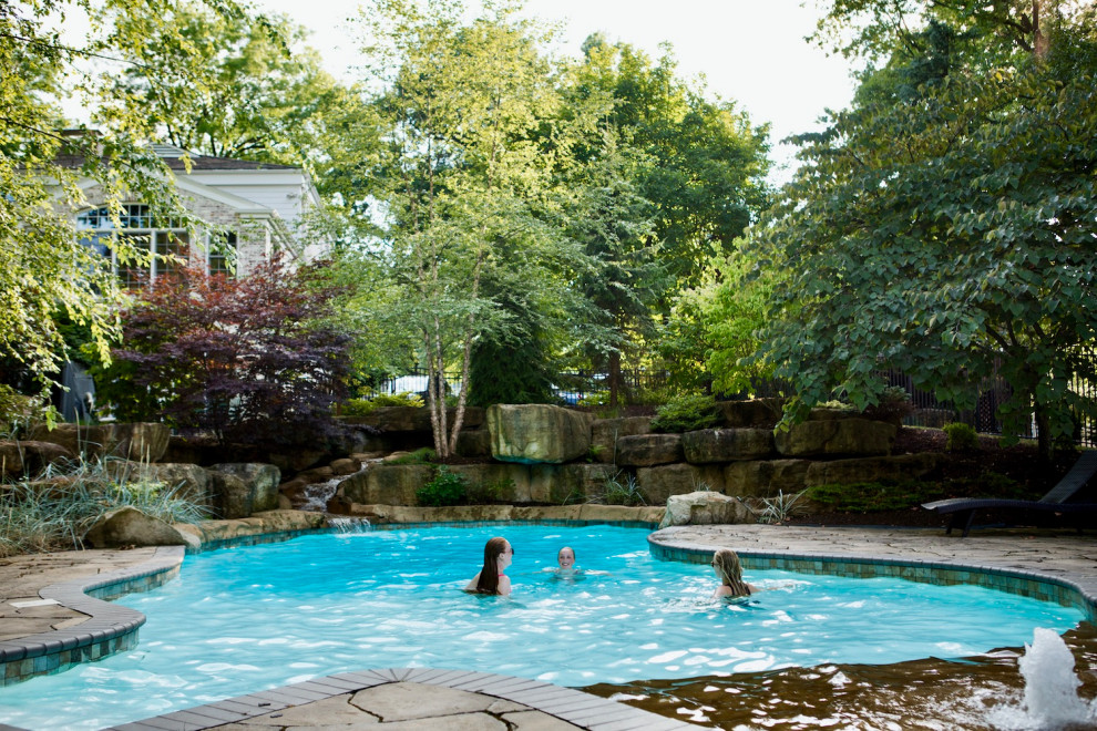 Esempio di una grande piscina naturale classica personalizzata dietro casa con paesaggistica bordo piscina e cemento stampato