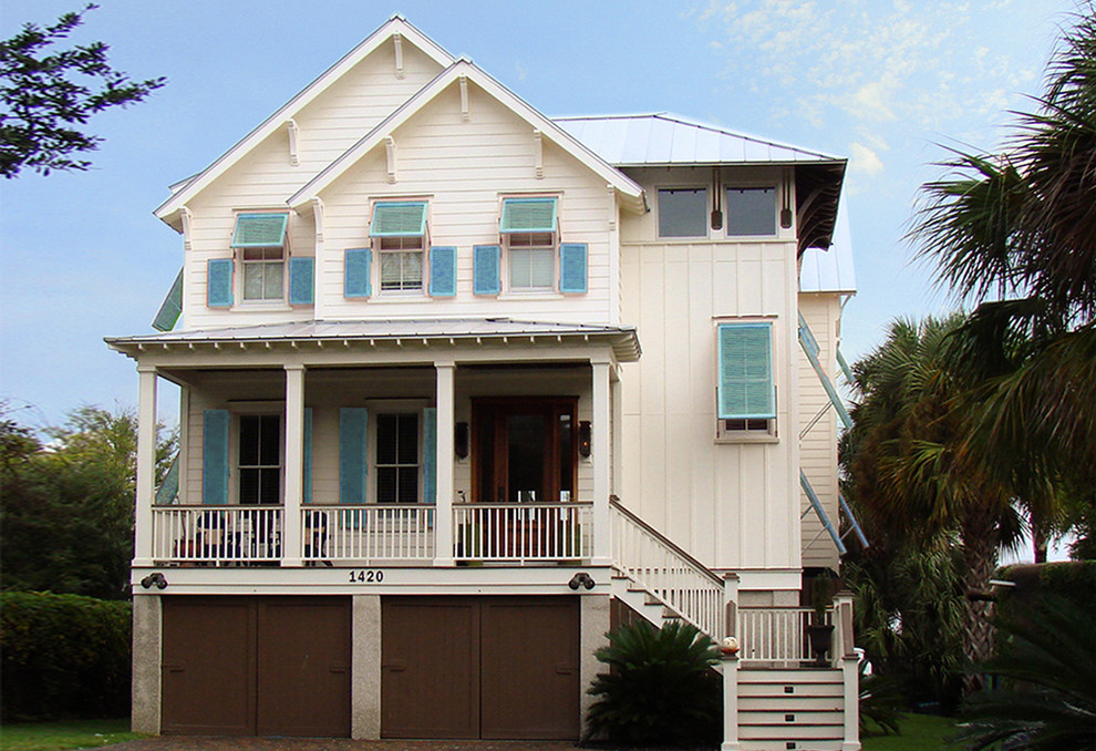 Photo of a large beach style two-storey white house exterior in Charleston with wood siding, a hip roof and a metal roof.