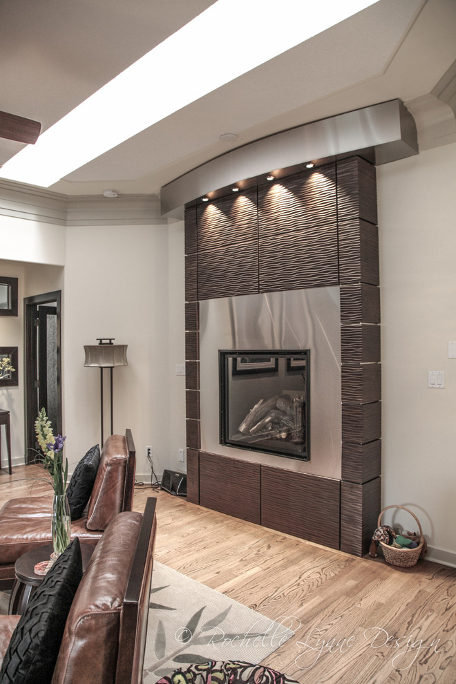 This is an example of a large contemporary open concept living room in Calgary with white walls, a standard fireplace, a metal fireplace surround, no tv and medium hardwood floors.