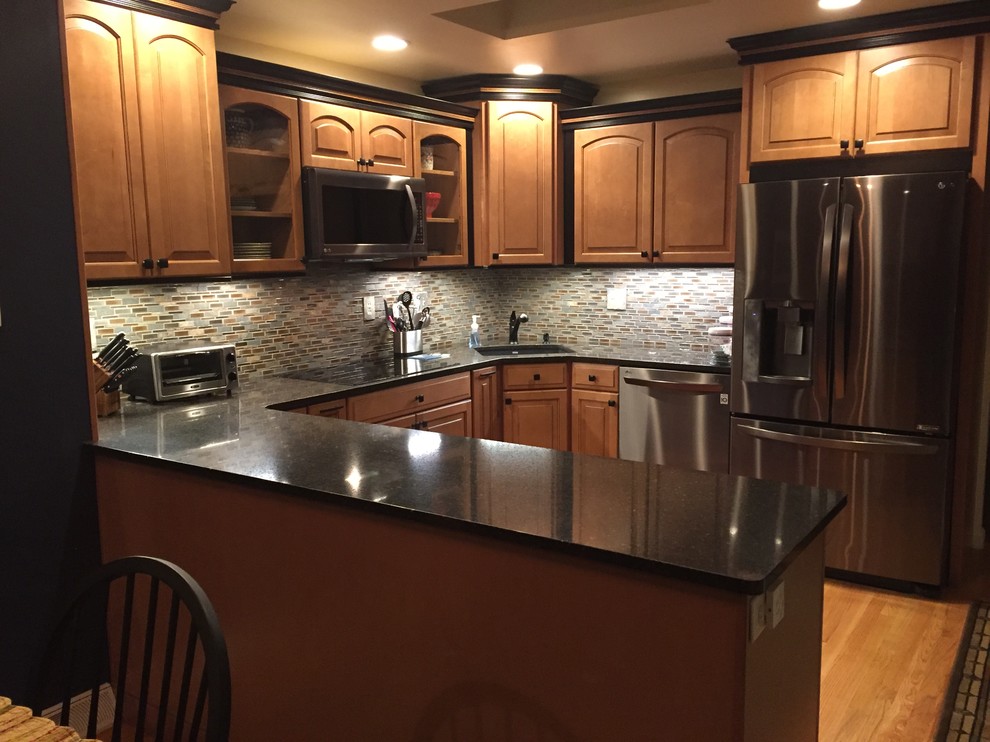 Kitchen - small rustic u-shaped light wood floor kitchen idea with a single-bowl sink, raised-panel cabinets, brown cabinets, quartz countertops and mosaic tile backsplash