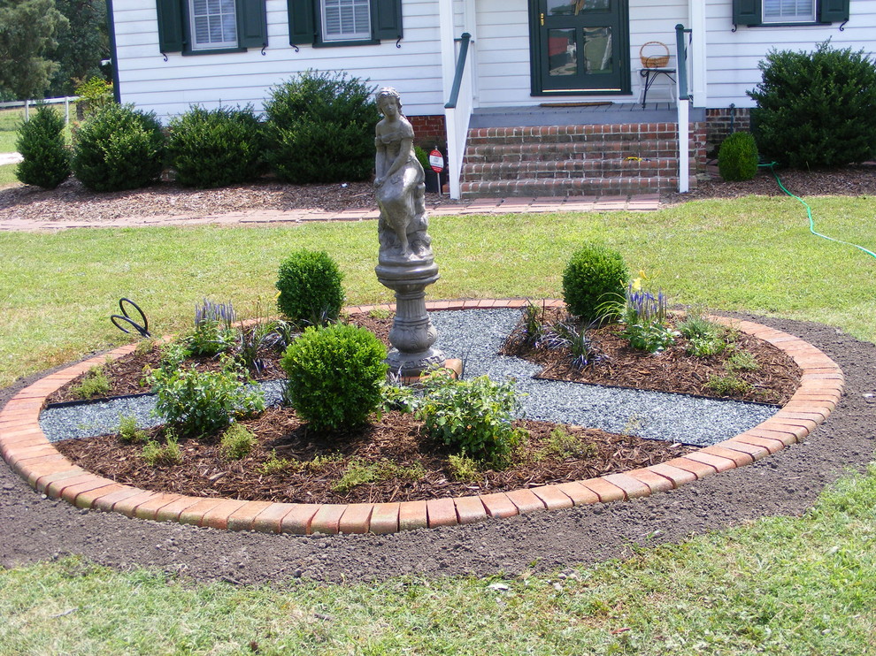 This is an example of a small traditional front yard full sun formal garden for summer in Other with a garden path and gravel.