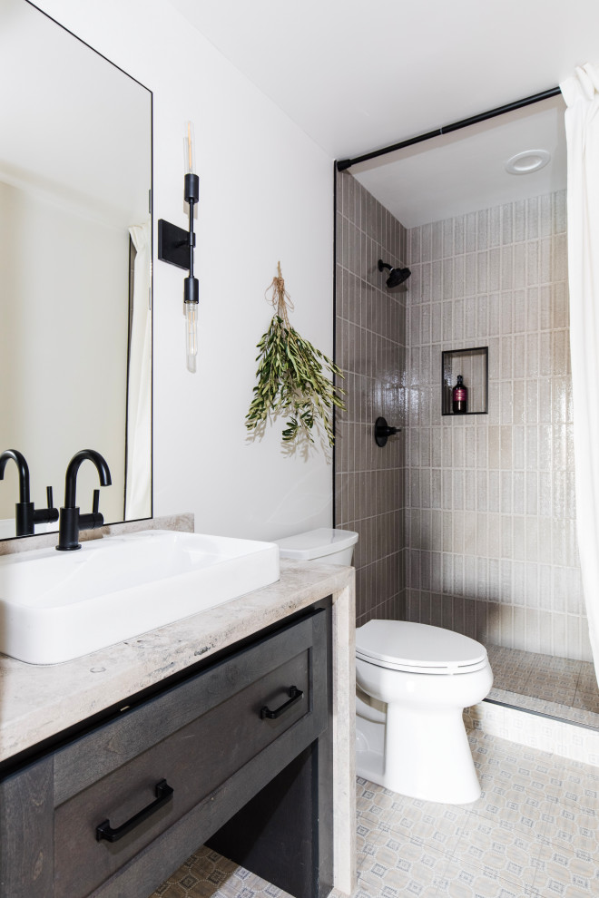 This is an example of a transitional bathroom in Phoenix with shaker cabinets, black cabinets, an alcove shower, gray tile, white walls, a vessel sink, beige floor, a shower curtain, beige benchtops, a single vanity and a built-in vanity.