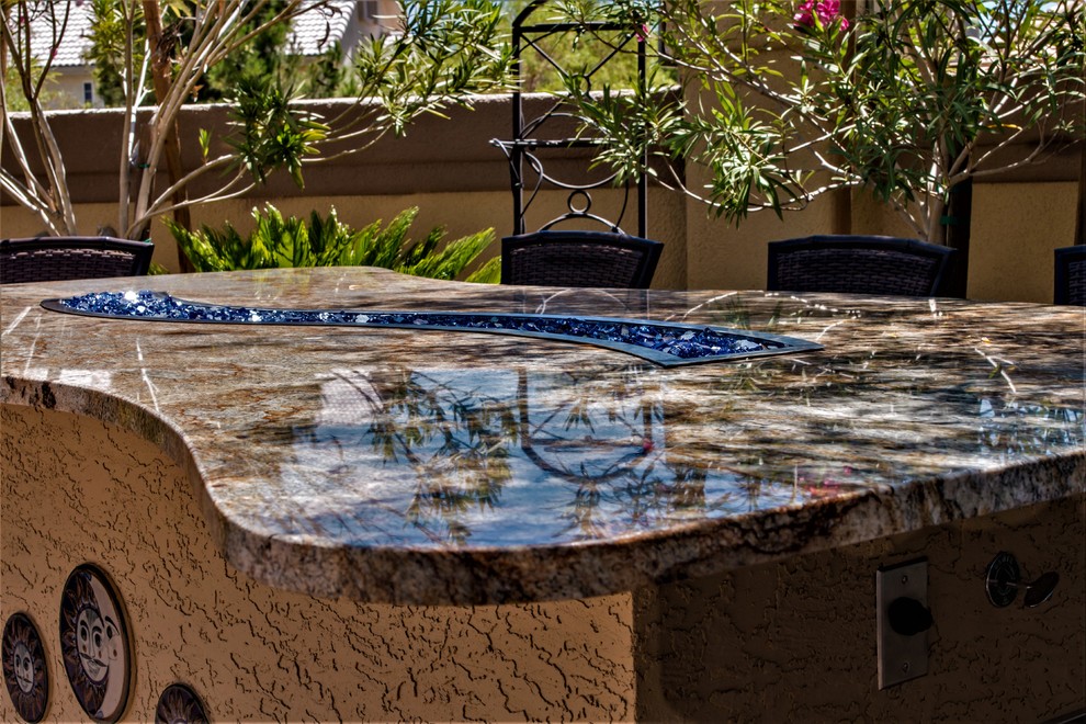 Inspiration for a large backyard patio in Las Vegas with an outdoor kitchen, brick pavers and a roof extension.