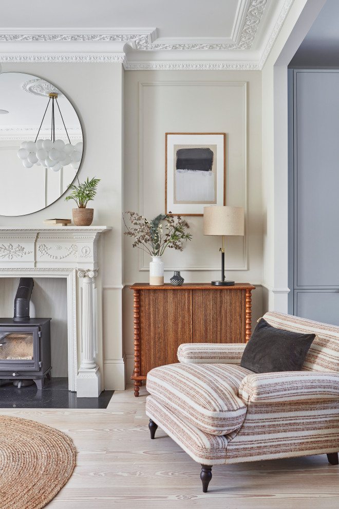Design ideas for a medium sized scandi enclosed living room in London with white walls, light hardwood flooring, a wood burning stove, a stone fireplace surround, no tv, brown floors, panelled walls and a chimney breast.