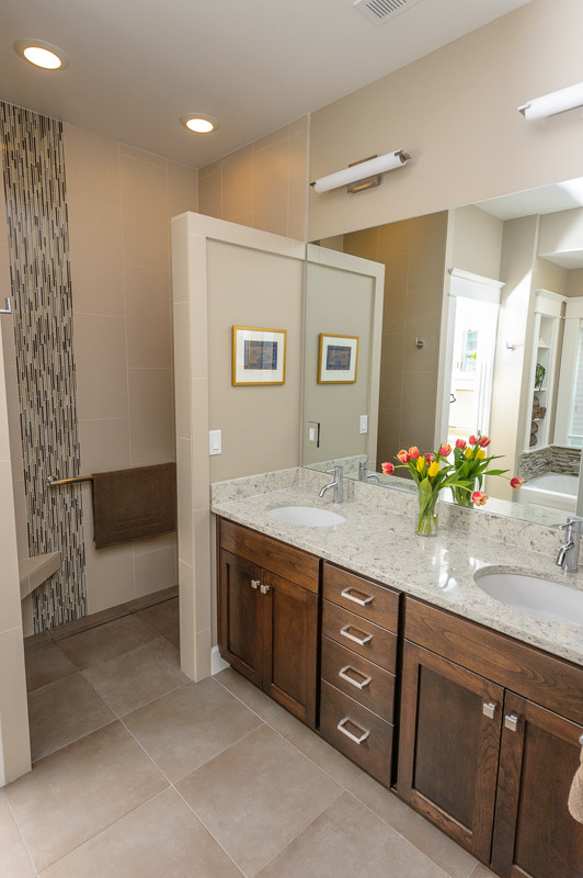 This is an example of a mid-sized arts and crafts master bathroom in Portland with recessed-panel cabinets, dark wood cabinets, an alcove tub, a curbless shower, a one-piece toilet, beige tile, glass tile, beige walls, ceramic floors, an undermount sink, engineered quartz benchtops, beige floor and an open shower.