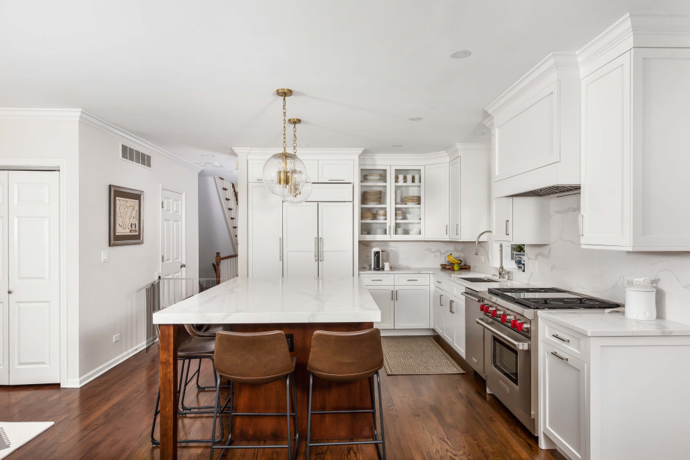 Design ideas for a small transitional l-shaped eat-in kitchen in Chicago with an undermount sink, shaker cabinets, white cabinets, quartz benchtops, white splashback, stone slab splashback, white appliances, dark hardwood floors, with island, brown floor and white benchtop.