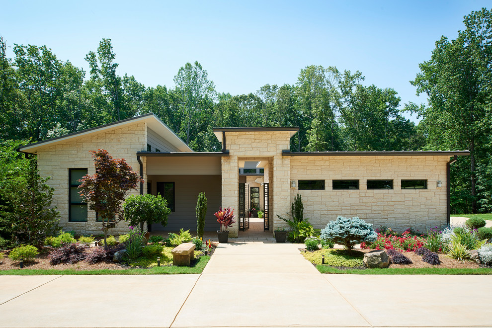 This is an example of a mid-sized modern one-storey beige house exterior in Atlanta with stone veneer, a flat roof and a metal roof.