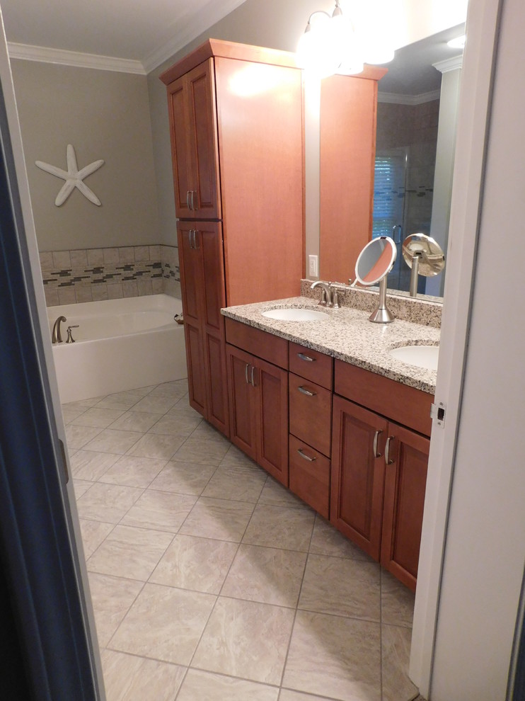 Inspiration for a large transitional master gray tile and ceramic tile ceramic tile corner bathtub remodel with raised-panel cabinets, medium tone wood cabinets, a two-piece toilet, beige walls, an undermount sink and granite countertops