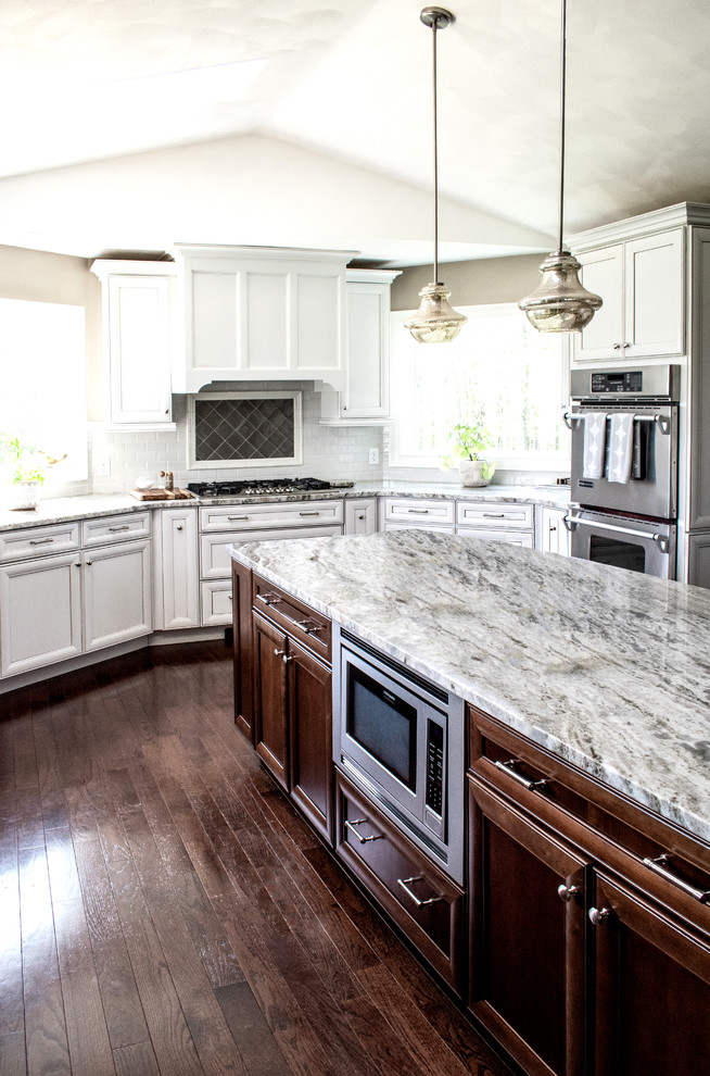 Inspiration for a transitional u-shaped dark wood floor and brown floor eat-in kitchen remodel in New York with an undermount sink, recessed-panel cabinets, white cabinets, granite countertops, multicolored backsplash, glass tile backsplash, stainless steel appliances, an island and multicolored countertops