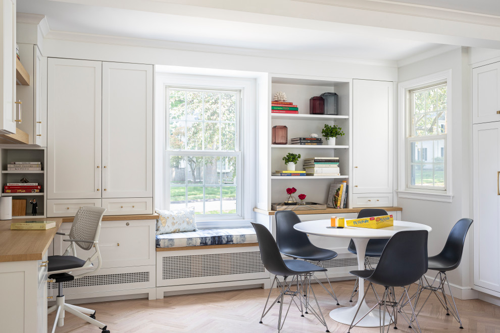 Klassisches Arbeitszimmer mit weißer Wandfarbe, hellem Holzboden, Einbau-Schreibtisch und beigem Boden in New York