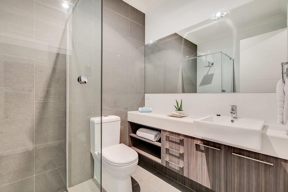 Mid-sized contemporary master bathroom in Adelaide with a drop-in sink, flat-panel cabinets, medium wood cabinets, laminate benchtops, a drop-in tub, a corner shower, a one-piece toilet, gray tile, porcelain tile, white walls and porcelain floors.