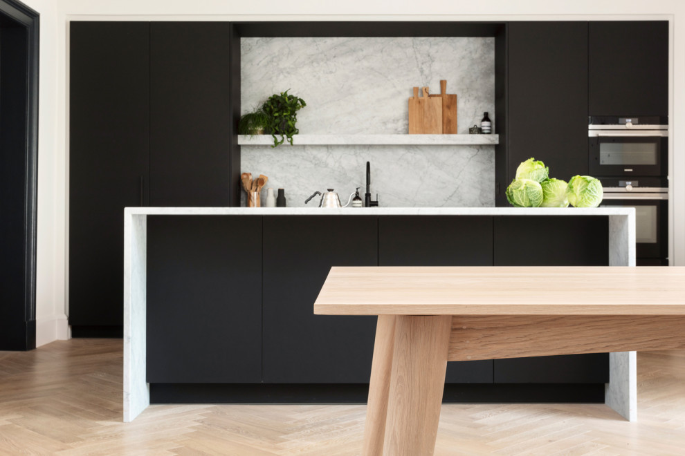 Mid-sized scandinavian single-wall eat-in kitchen in Edinburgh with an undermount sink, flat-panel cabinets, black cabinets, marble benchtops, grey splashback, marble splashback, black appliances, light hardwood floors, with island, brown floor, grey benchtop and wallpaper.