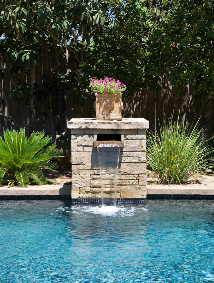 Design ideas for a mid-sized traditional backyard rectangular natural pool in Austin with a water feature and natural stone pavers.