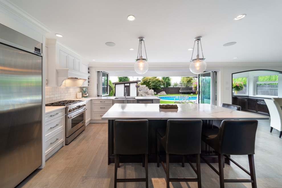 Inspiration for a transitional beige floor kitchen remodel in Vancouver with white backsplash, stainless steel appliances, an island and white countertops