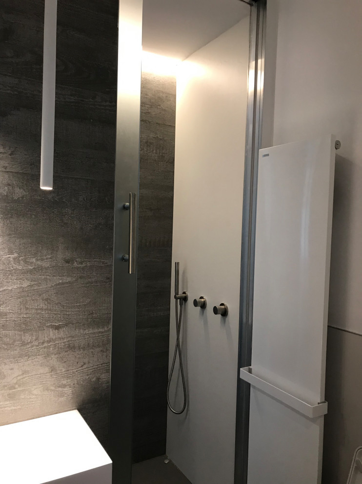 Inspiration for a small modern 3/4 bathroom in Bologna with flat-panel cabinets, white cabinets, a double shower, a wall-mount toilet, gray tile, porcelain tile, white walls, porcelain floors, a console sink, solid surface benchtops, grey floor, a sliding shower screen and white benchtops.