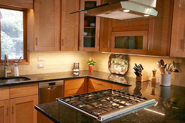 Eat-in kitchen - small transitional l-shaped porcelain tile eat-in kitchen idea with shaker cabinets, light wood cabinets, granite countertops, beige backsplash, glass tile backsplash, stainless steel appliances and a peninsula
