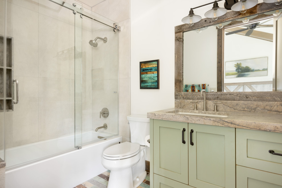 Photo of a medium sized rustic family bathroom in Salt Lake City with recessed-panel cabinets, green cabinets, an alcove bath, a shower/bath combination, a two-piece toilet, beige tiles, limestone tiles, white walls, wood-effect flooring, a submerged sink, quartz worktops, multi-coloured floors, a sliding door, beige worktops, a wall niche, a single sink and a built in vanity unit.