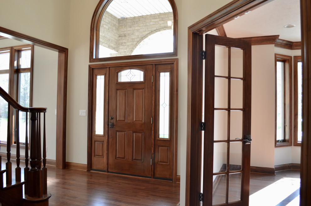 Example of a transitional medium tone wood floor and brown floor entryway design with gray walls and a medium wood front door