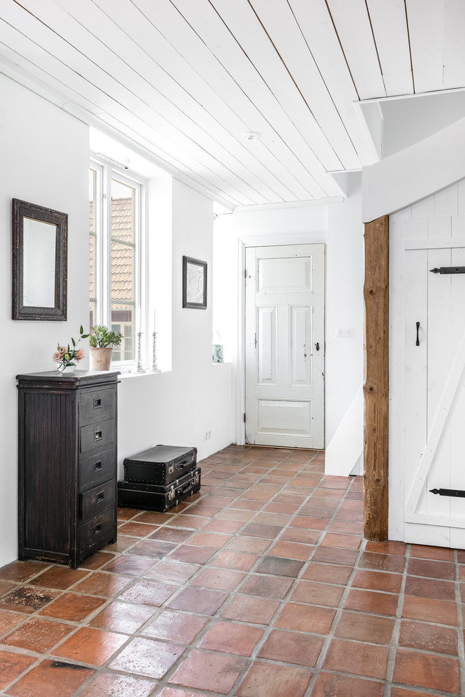Country hallway in Malmo with white walls and terra-cotta floors.