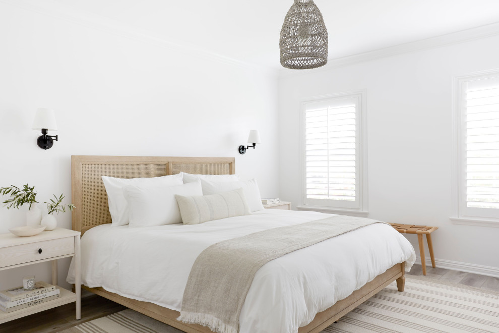 This is an example of a transitional guest bedroom in Los Angeles with white walls, light hardwood floors, no fireplace and brown floor.