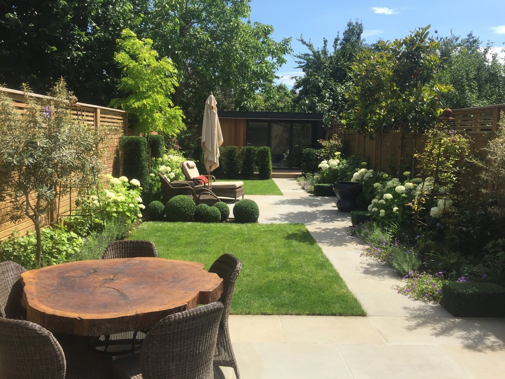 Photo of a mid-sized contemporary backyard garden in London with natural stone pavers.