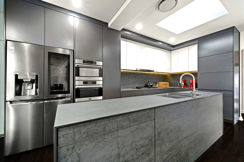 Inspiration for a mid-sized contemporary l-shaped kitchen in Sydney with a double-bowl sink, flat-panel cabinets, grey cabinets, quartz benchtops, grey splashback, porcelain splashback, stainless steel appliances, painted wood floors, with island, black floor and grey benchtop.