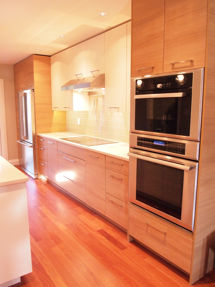 Contemporary galley eat-in kitchen in Vancouver with a double-bowl sink, flat-panel cabinets, light wood cabinets, quartz benchtops, beige splashback, ceramic splashback and stainless steel appliances.