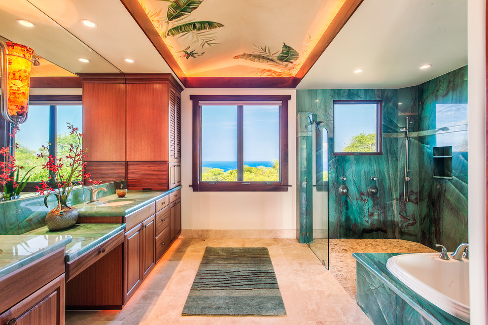 Inspiration for a large tropical master bathroom in Hawaii with an undermount sink, raised-panel cabinets, dark wood cabinets, granite benchtops, green tile, white walls, travertine floors, a drop-in tub, stone slab, a curbless shower and green benchtops.