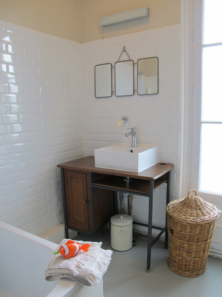This is an example of a mid-sized scandinavian kids bathroom in Paris with medium wood cabinets, a drop-in tub, white tile, ceramic tile, beige walls, concrete floors, a vessel sink, wood benchtops, grey floor and beige benchtops.