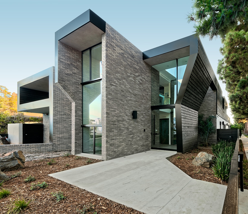 Photo of a large contemporary two-storey brick grey house exterior in Los Angeles with a flat roof.