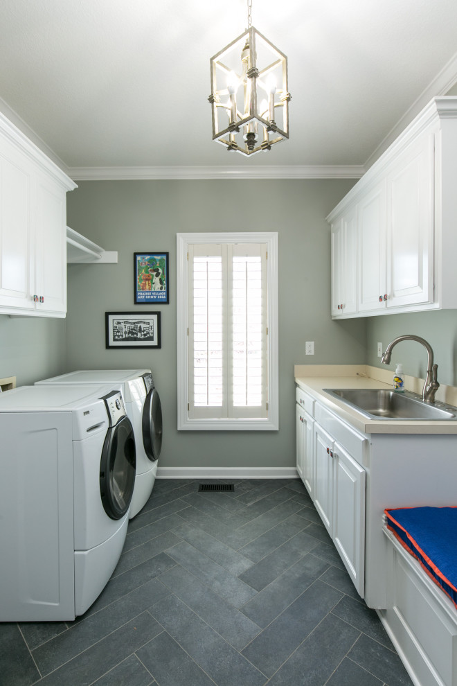 Design ideas for a medium sized traditional galley separated utility room in Kansas City with raised-panel cabinets, white cabinets, porcelain flooring, a side by side washer and dryer and black floors.