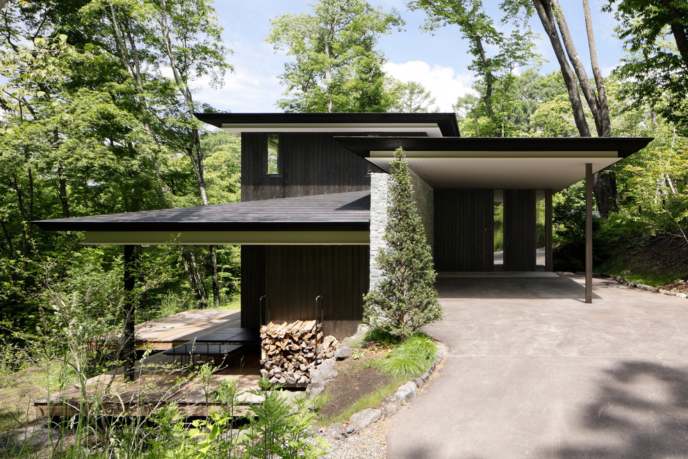 This is an example of a modern two-storey black house exterior in Other with wood siding, a hip roof and a metal roof.