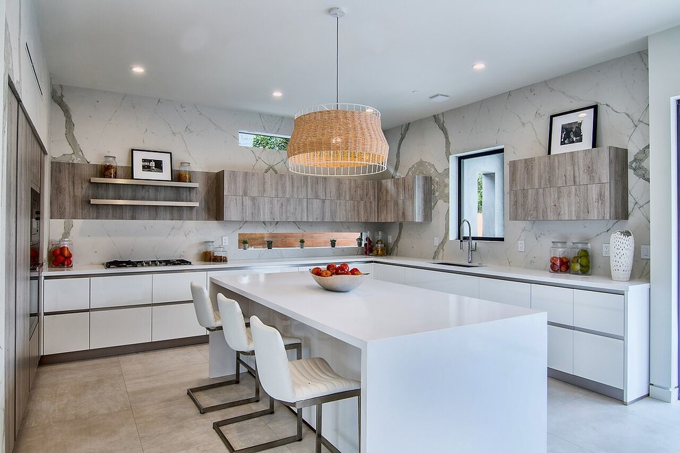 Inspiration for a mid-sized modern u-shaped separate kitchen in Hawaii with an undermount sink, flat-panel cabinets, white cabinets, solid surface benchtops, grey splashback, panelled appliances, porcelain floors, with island, brown floor and white benchtop.